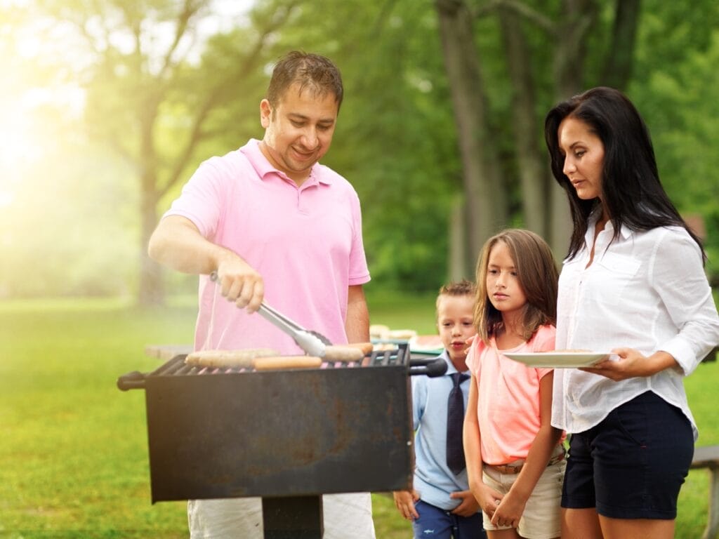 Grill a satisfying lunch outdoors in the summer sun like this family.