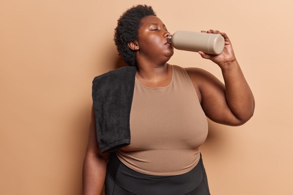 Athletic woman hydrating with water bottle after exercise session