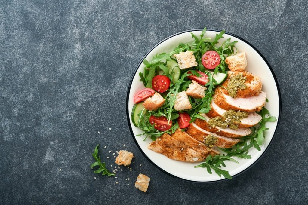 Balanced plate with sliced chicken breast and fresh arugula salad